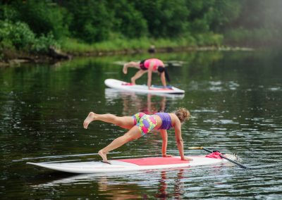 Young woman doing fitness on a board with an oar. Side view - the concept of harmony with nature, a free and healthy lifestyle, supernumerary staff